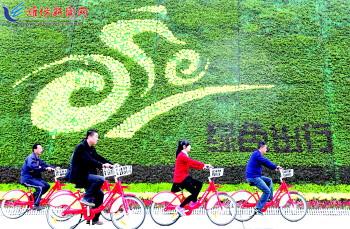 市民騎公共自行車路過市人民廣場一處花壇。記者 張馳